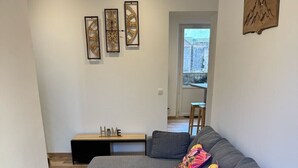A modern living room with a grey sectional sofa, wooden flooring, and a small wooden table with a 'HOME' sign.