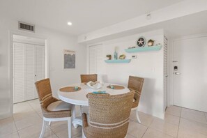 A dining area with a round table, four wicker chairs, and a white ceiling.