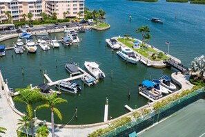 A marina with boats docked, a parking area, and a building with balconies overlooking the water.