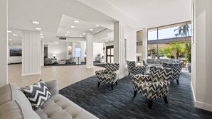 A spacious lobby with modern furniture, a large digital display, and a view of the outdoors.