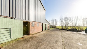 A large industrial building with a gravel driveway and a green metal fence. - Holiday Apartment 'Hühnerhort' with Shared Terrace, Garden and Wi-Fi (Sankt Annen)