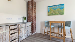 A kitchen with a rustic wooden cabinet, a brick chimney, and a dining area with two chairs. - Holiday Apartment 'Hühnerhort' with Shared Terrace, Garden and Wi-Fi (Sankt Annen)