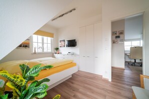 A bedroom with a bed, a desk, a TV, and a wardrobe. - Holiday Home 'Rügenblick 24' with Sea View, Private Terrace and Wi-Fi (Kramerhof)