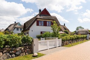 A traditional house with a thatched roof, a stone wall, and a paved driveway. - Holiday Home 'Rügenblick 24' with Sea View, Private Terrace and Wi-Fi (Kramerhof)