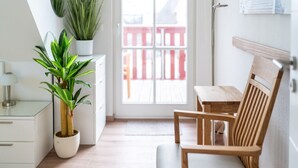 Moderni, pelkistetty huone, jossa on puinen tuoli, pieni pöytä, ruukkukasvi ja laatikoilla varustettu työpöytä.