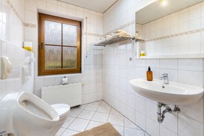A bathroom with a toilet, a sink, a window, and a towel rack. - Apartment '55qm' with Private Terrace, Private Garden and Wi-Fi (Herscheid)