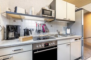 Eine moderne Küche mit Mikrowelle, Kaffeemaschine und Edelstahlgeräten.