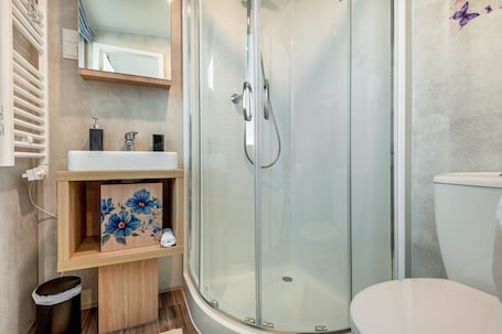 Ein modernes Badezimmer mit einer gläsernen Duschkabine, einem weißen Waschbecken und einer Toilette.. Tiny Home 'Sankt Rupert Nummer 11' mit privater Terrasse und Klimaanlage