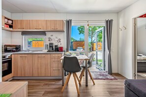 Une cuisine moderne avec des meubles en bois, une table à manger avec des chaises et une vue à travers la porte vitrée.