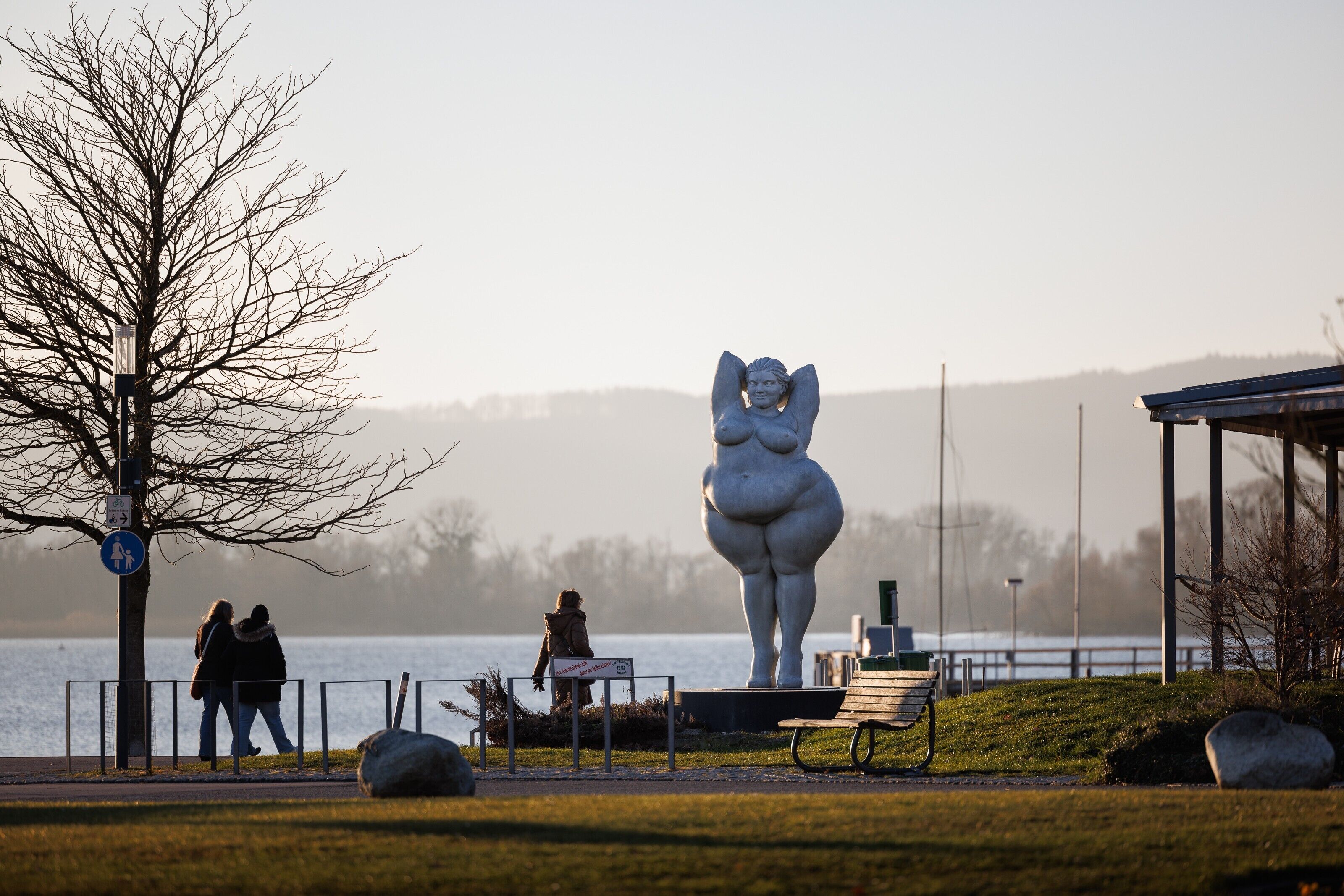 A park with a large statue, a bench, and a path.