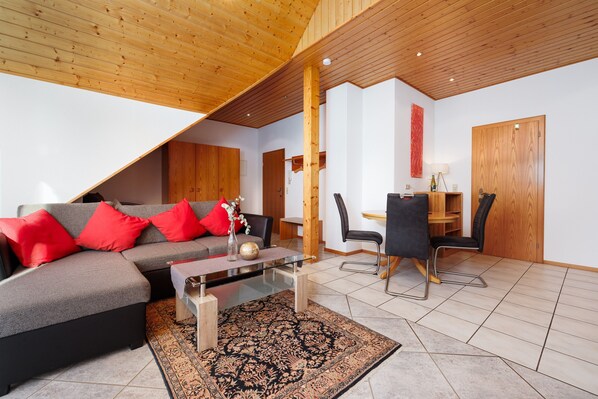 A modern living room with a sectional sofa, a coffee table, and a dining area with a table and chairs.