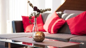A glass coffee table with a vase containing dried flowers and greenery, placed on a wooden floor.