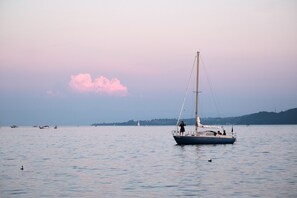 A sailboat on calm water with a distant shoreline and a pinkish sky. - Guest Room 1 with Balcony and Wi-Fi (Bodman-Ludwigshafen)