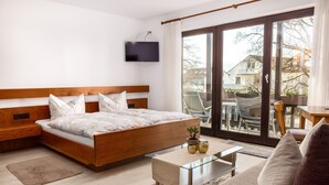Un dormitorio con cama, televisor, sofá y balcón con vistas.