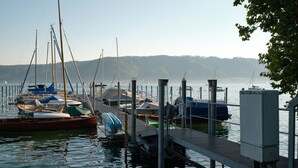 Un puerto deportivo con barcos amarrados, un muelle y una colina boscosa al fondo.