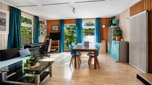 Un salon moderne comprenant un coin repas, un parquet et de grandes fenêtres avec des rideaux.