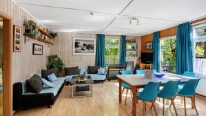 Un salon moderne comprenant un canapé, une table basse et un coin repas avec des chaises.
