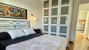 Een slaapkamer met een bed, een nachtkastje, een wandlamp en een groot raam met geëtste glaspanelen.