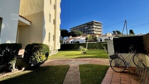 Een erf met een verhard pad, een fiets en een gebouw met meerdere balkons.