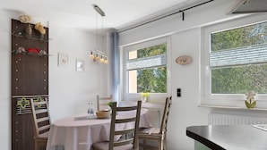 A dining area with a table, chairs, and a window with blinds.