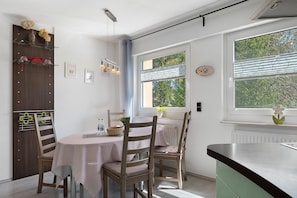 Ein Essbereich mit Tisch, Stühlen und einem Fenster mit Jalousien.