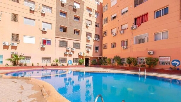 A swimming pool surrounded by multi-story buildings with air conditioning units.