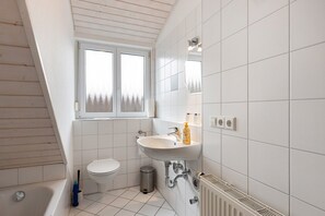A modern bathroom with a bathtub, toilet, and sink. - Holiday Apartment at the Orchard, 70sqm with Balcony and Wi-Fi (Bodman-Ludwigshafen)