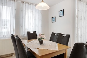 A dining table with chairs, a potted plant, and a table runner. - Holiday Apartment at the Orchard, 70sqm with Balcony and Wi-Fi (Bodman-Ludwigshafen)