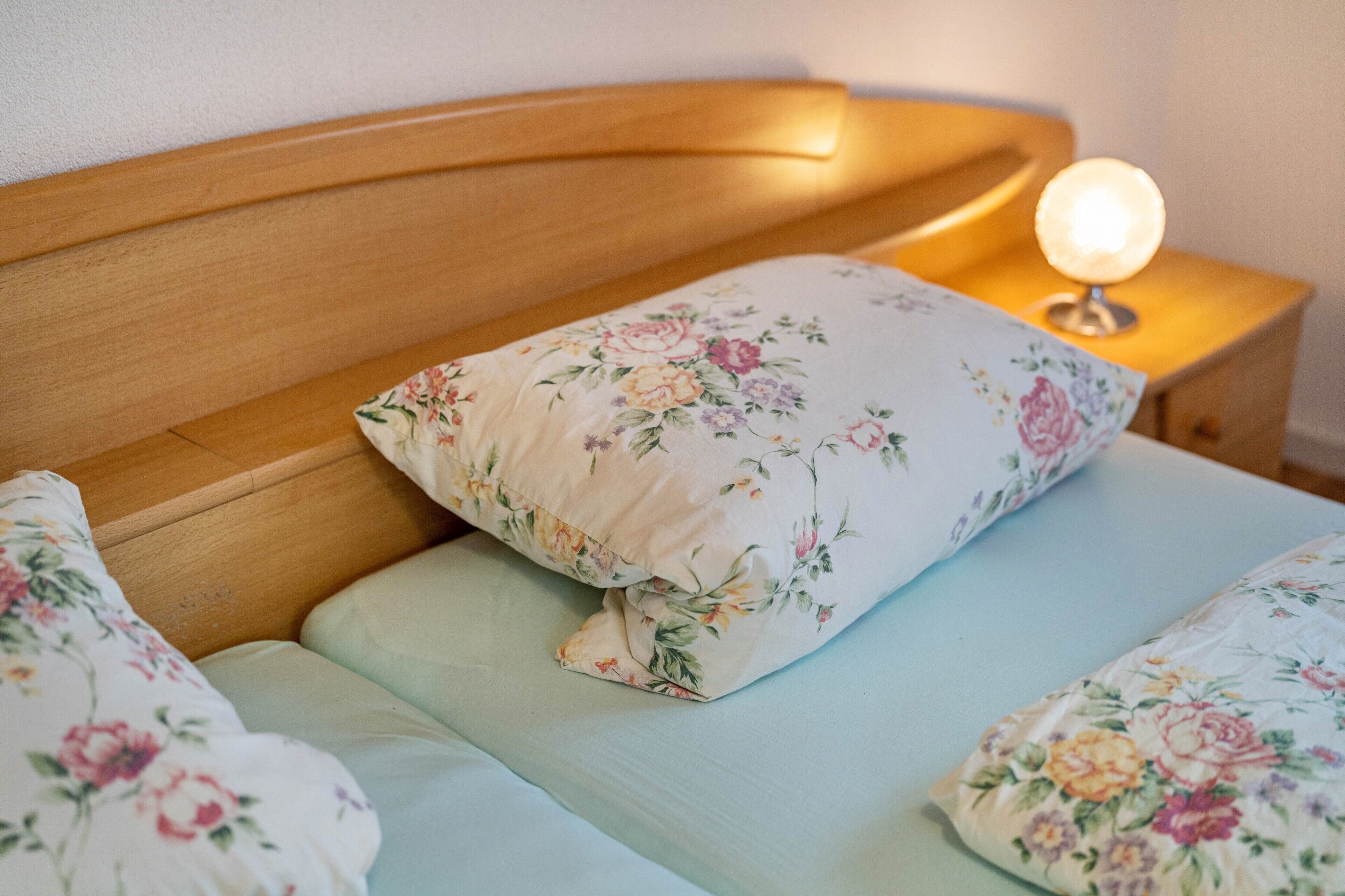A bed with floral bedding and a bedside lamp.
