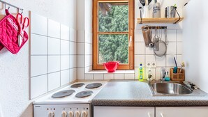 Una cocina con estufa Siemens, una ventana con vista a árboles y varios utensilios de cocina en estantes.