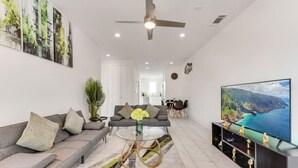 A modern living room with a sofa, coffee table, and a TV displaying a scenic view.
