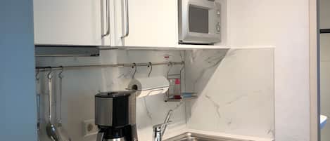 A compact kitchen with a built-in microwave, a coffee maker, and a sink.