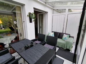 A conservatory with a table and chairs, a sofa with cushions, and a potted plant. - Apartment '1' with Private Terrace, Shared Garden and Wi-Fi (Meersburg)