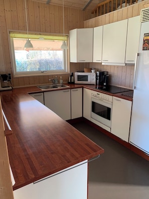 Eine Küche mit Holzausstattung, einer Mikrowelle, einer Kaffeemaschine und einem Kühlschrank.
