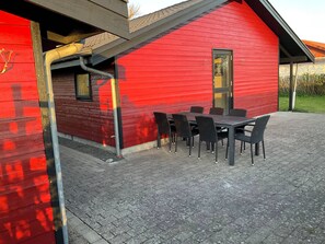 Ein rotes Gebäude mit einer überdachten Terrasse, komplett mit Tisch und Stühlen.