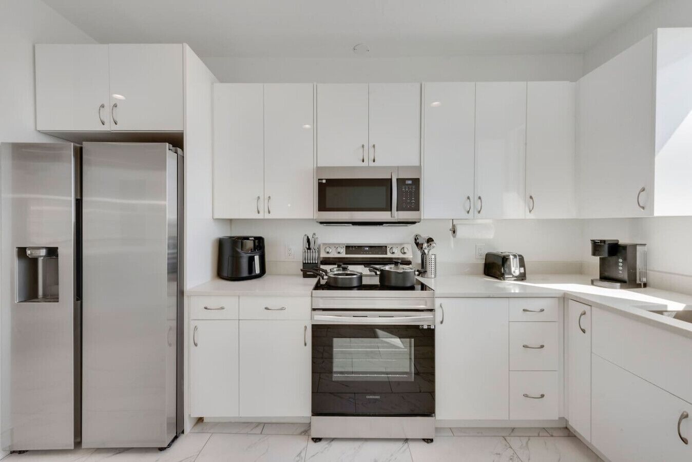 A modern kitchen with white cabinets, stainless steel appliances, and a built-in oven.