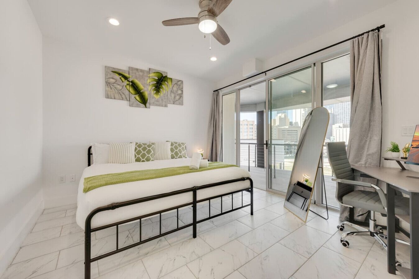 A bedroom with a bed, a desk, a chair, and a ceiling fan.