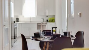 Een moderne keuken met witte kastjes, een eettafel gedekt met borden, glazen en een klein zandloper.