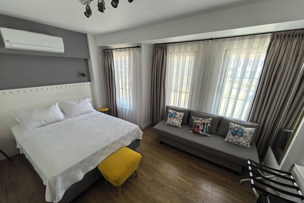 A modern hotel room with a bed, a sofa, a small table, and a chair.
