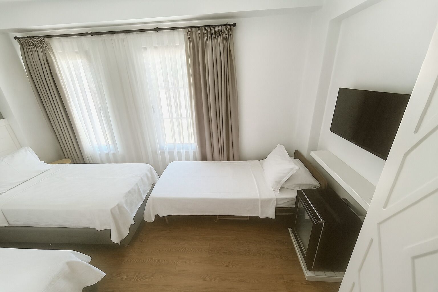 A hotel room with two single beds, a TV, and a small table.