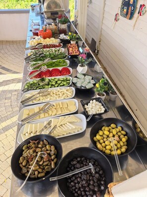 A buffet table with various food items and utensils. - QonuQ Bozcaada (Bozcaada)