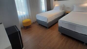 Una habitación de hotel con dos camas, un pequeño taburete amarillo y un mueble negro.