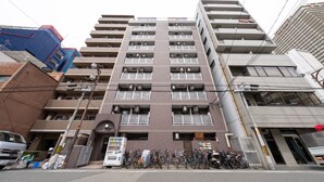 Een meerlaags gebouw met een gelijkmatige gevel, balkons en een rij fietsen ervoor geparkeerd.