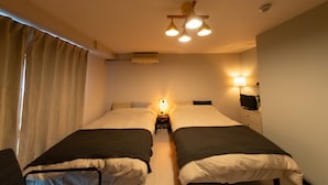 Een hotelkamer met twee eenpersoonsbedden, een nachtkastje met lamp, een plafondlamp en een tv aan de muur.