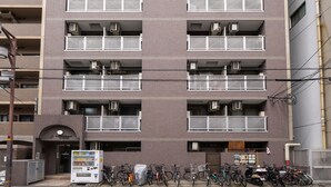 Een meerlaags gebouw met balkons, een automaat en fietsen die ervoor geparkeerd staan.