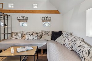A loft-style bedroom with a large bed, a wooden ceiling, and two wall-mounted shelves.