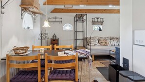 A dining area with a wooden table and chairs, a basket, and a hanging light fixture.