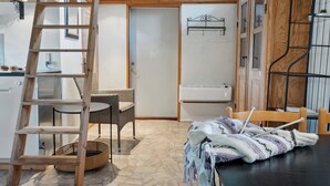 A room with a wooden ladder, wicker chair, and a table with a blanket.