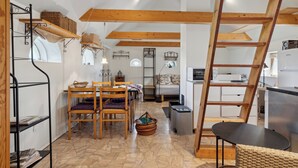 A compact living space with a dining area, kitchen, and a loft bedroom.