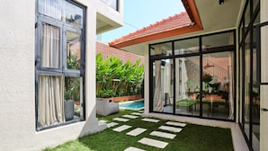 Una casa moderna con piscina, un piccolo giardino con lastre di pietra e un patio.